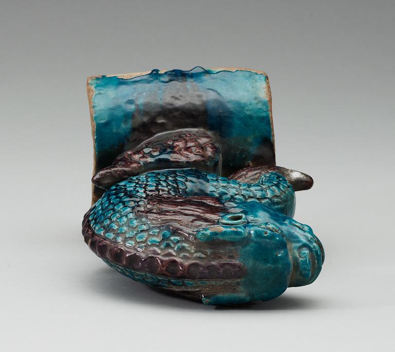 A turquoise and purple glazed roof top tile in the shape of a fish, Ming dynasty.