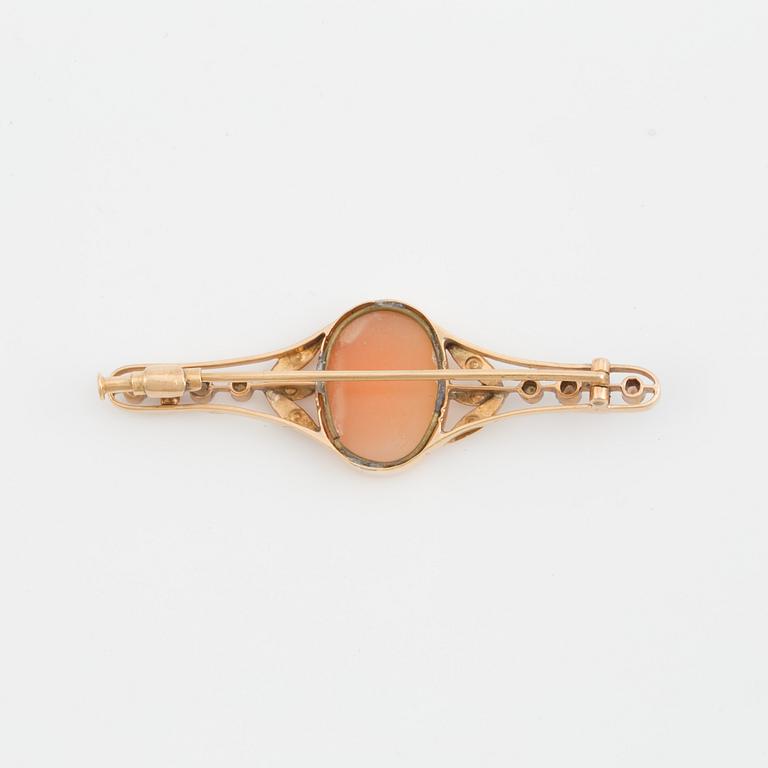 A brooch set with a shell cameo, seed pearls and probably synthetic rubies.