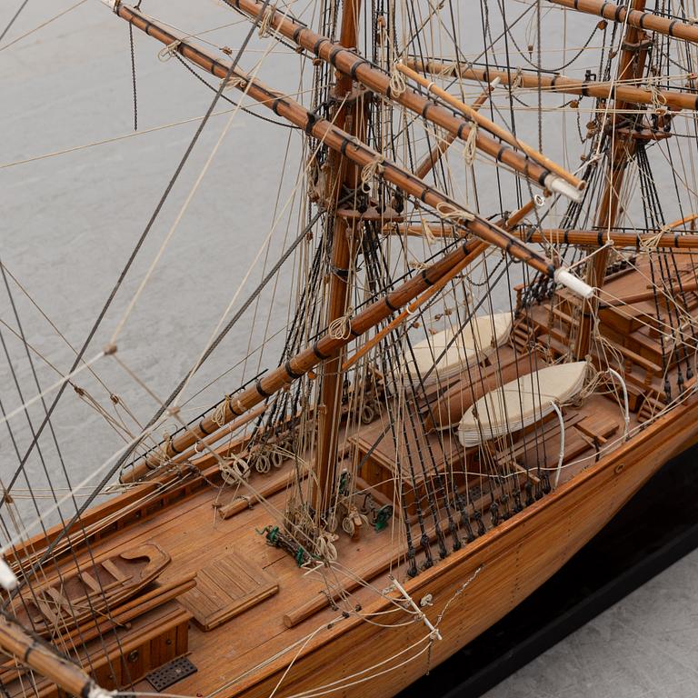 A wooden scale model of Cutty Sark on a painted wooden stand.