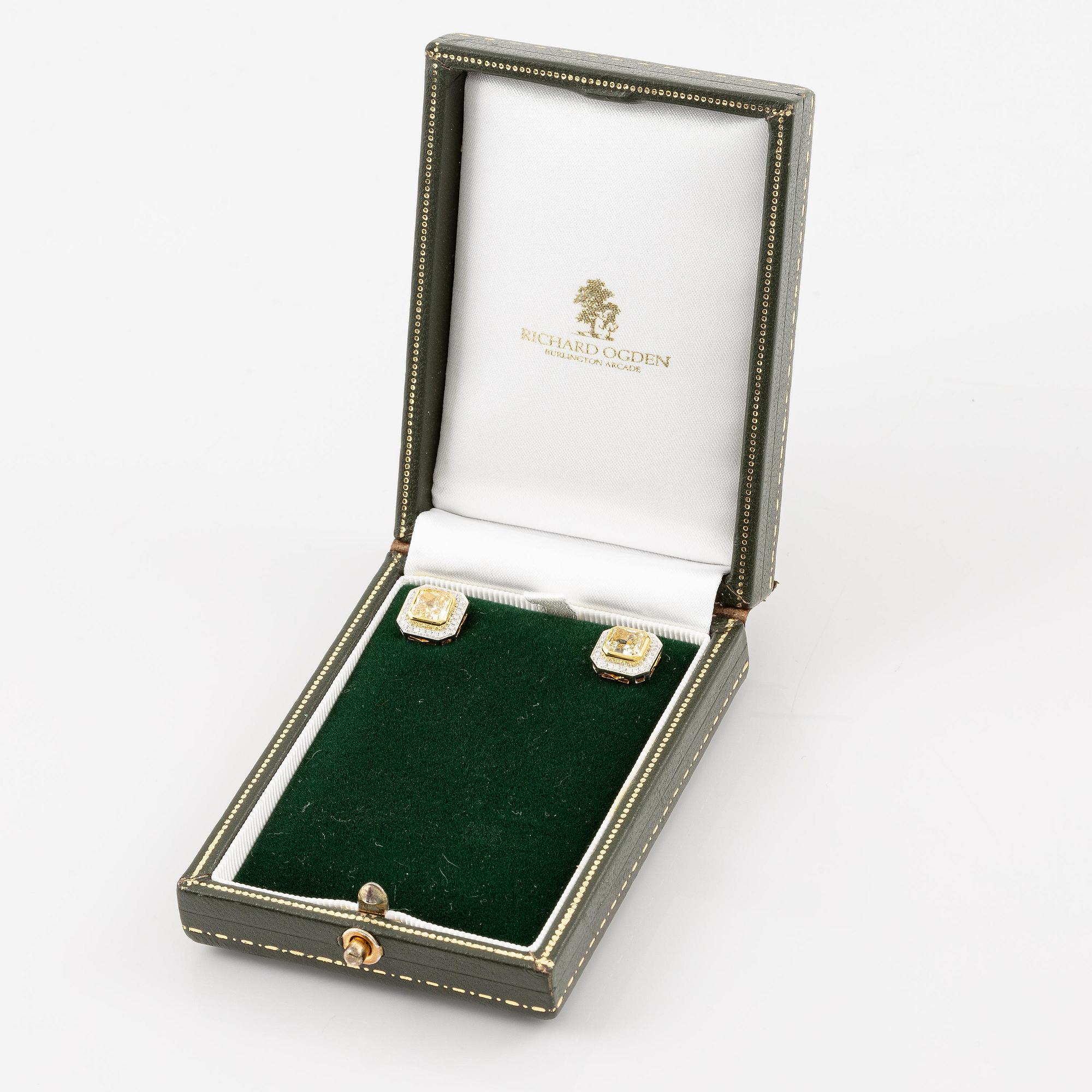 A pair of platinum and gold earrings with two radiant-cut yellow diamonds.