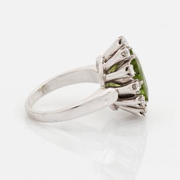 An 18K white gold ring set with a faceted peridot and round brilliant-cut diamonds.