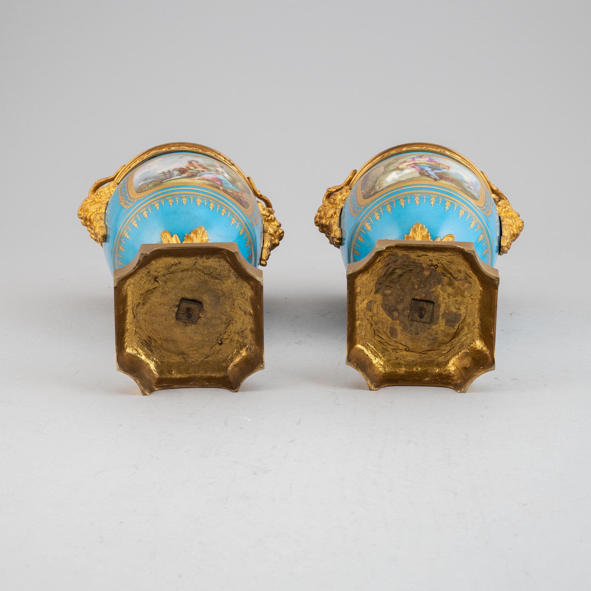 A pair of pordelain and gilt brass urns in teh style of Sevres, 20th Century.