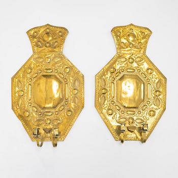 A pair of Baroque style brass wall sconces form around the year 1900.