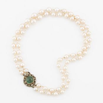 Necklace, double-stranded with cultured pearls, clasp by Engelbert Stigbert in 18K gold with cabochon-cut emerald and white stones.