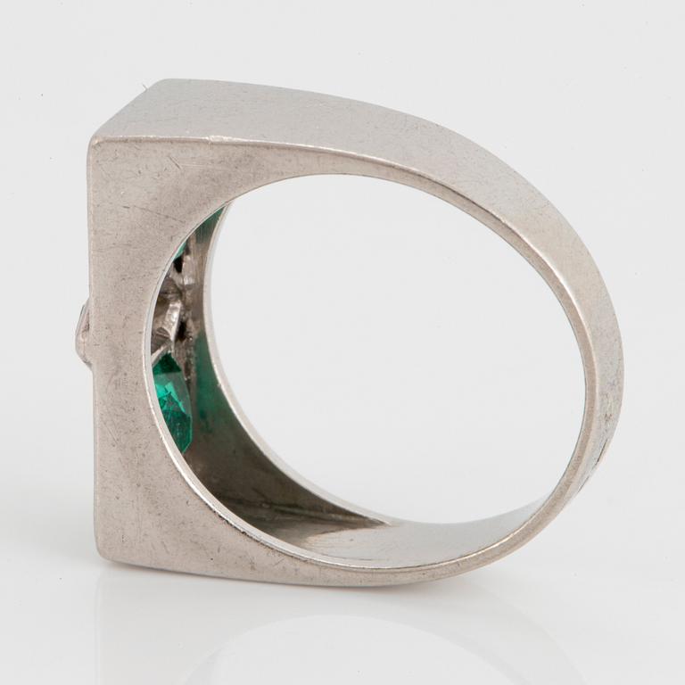 A platinum ring set with faceted emeralds and diamonds.