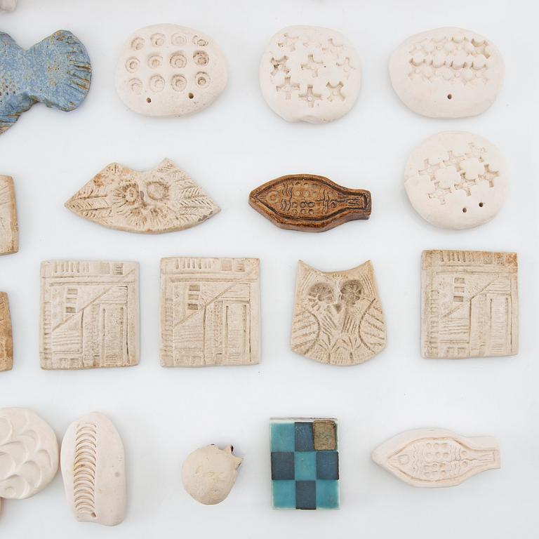 Anita Nylund, ca 39 st. pärlor, plaketter, miniatyrhuvuden mm. Egen verkstad.
