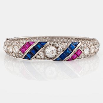 1049. A platinum bangle set with old- and rose-cut diamonds and faceted sapphires and rubies.