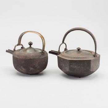 A set of two Japanese early 20th century cast iron chōshi (銚子).