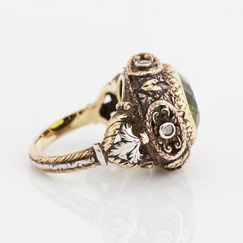 A silver and gold ring set with a faceted peridot and rose-cut diamonds.