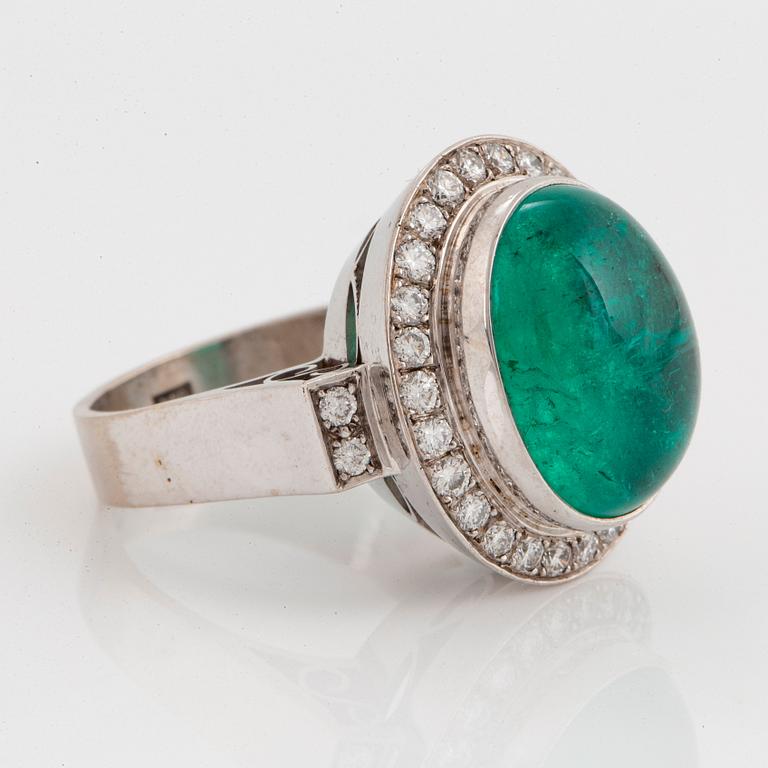 An 18K white gold ring set with a cabochon-cut emerald and round brilliant-cut diamonds.