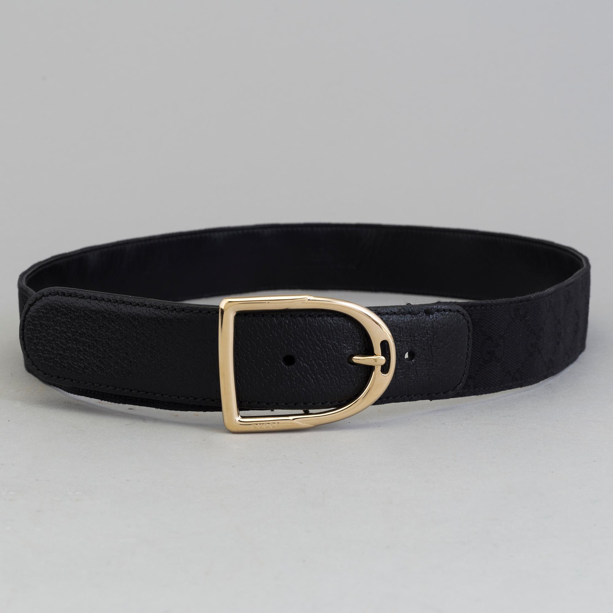 A blach monogram belt by Gucci.