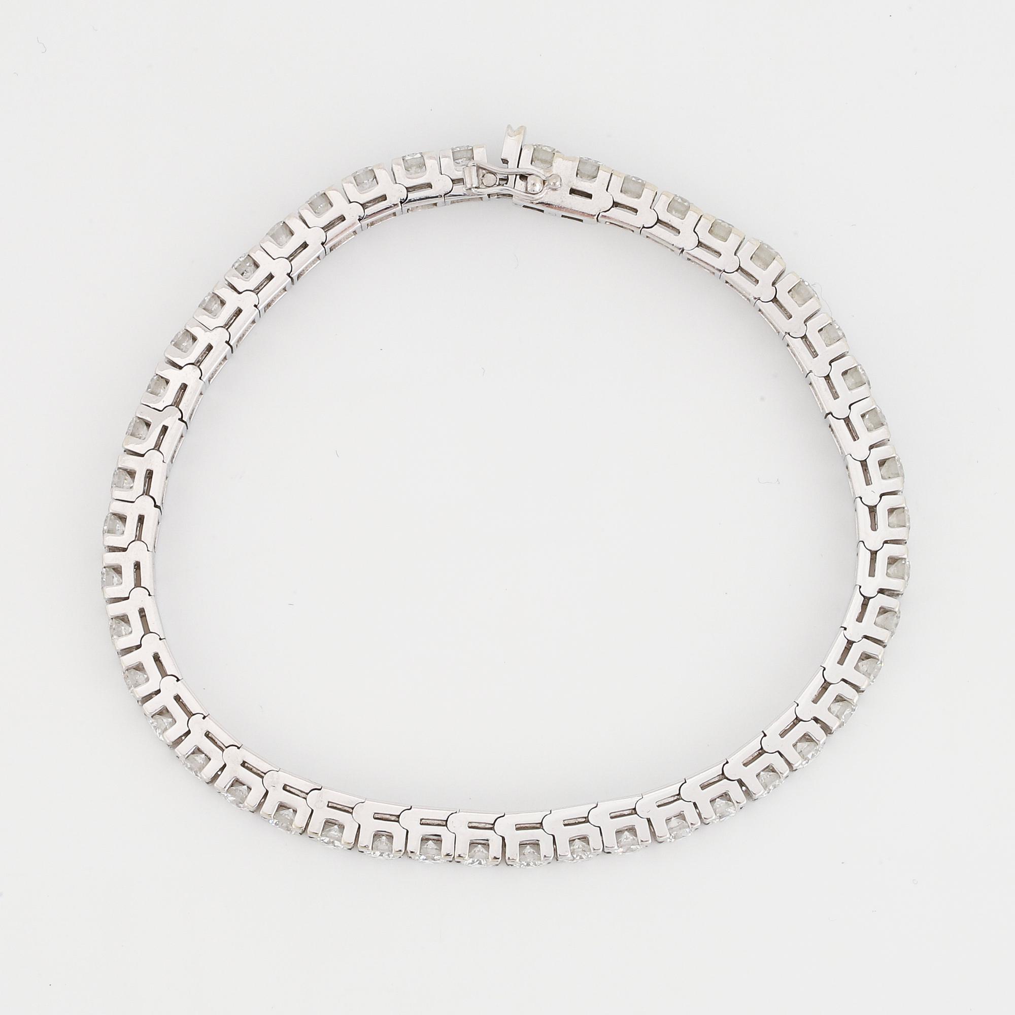 An 18K white gold tennisbraclet set with round brilliant-cut diamonds.