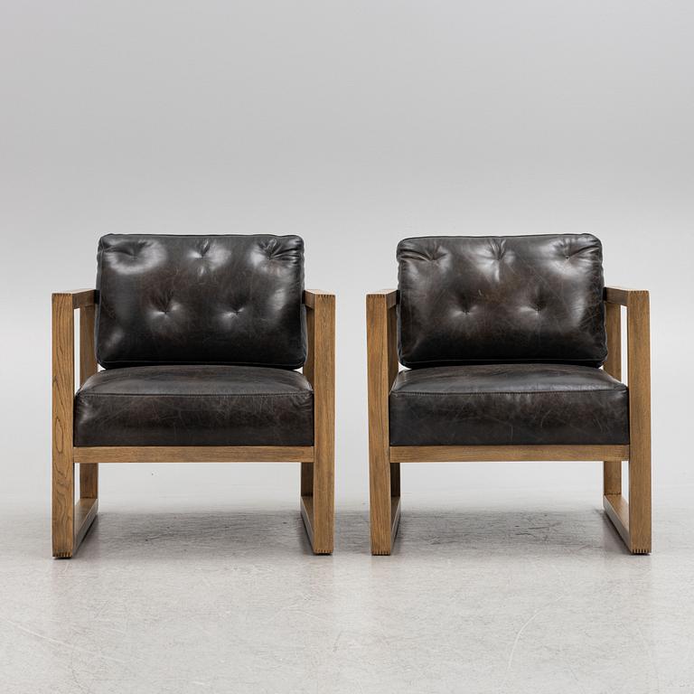 A pair of oak easy chairs with leather upholstered cushions from Artwood.