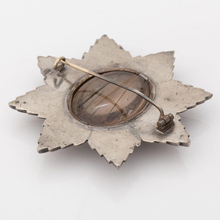 A brooch in grey metal set with rutile quartz.