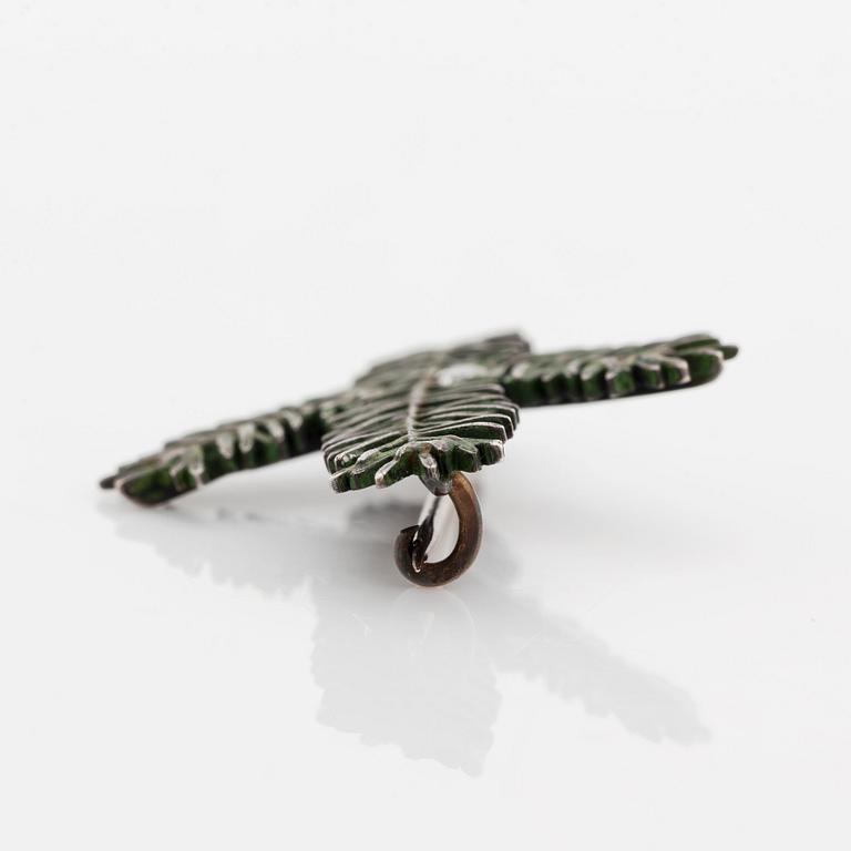 Brosch silver och emalj med en rund briljantslipad diamant.