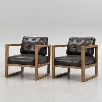 A pair of oak easy chairs with leather upholstered cushions from Artwood.