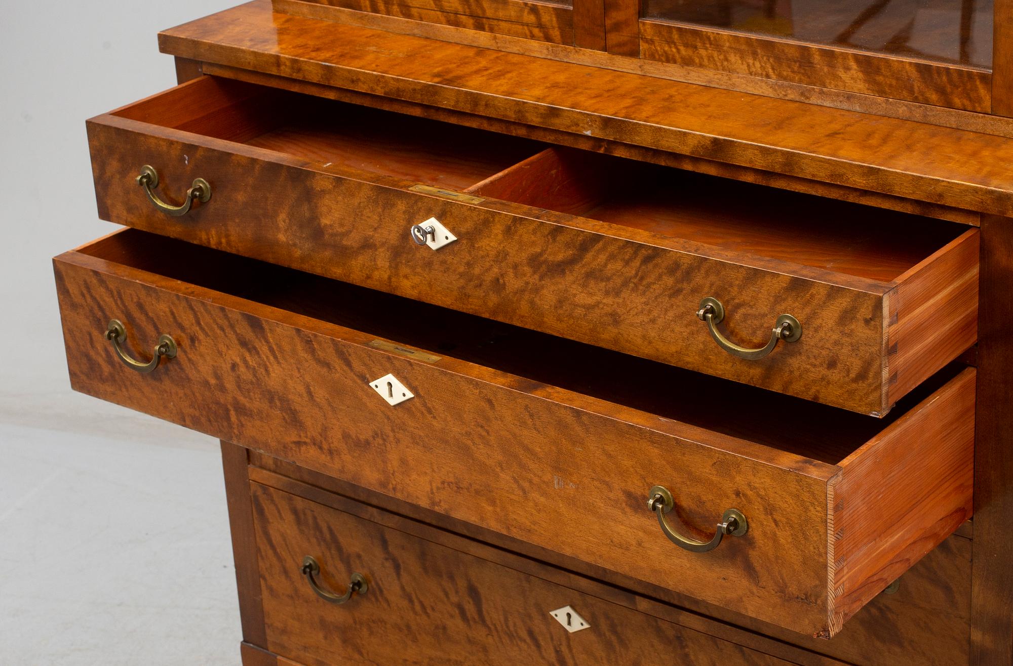 a chest of drawers with a vitrine cabinet from the early 20th century.