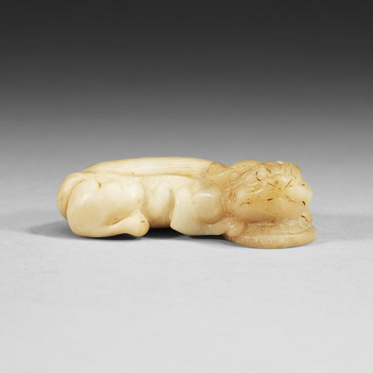 A Chinese nephrite figure of a reclining buddhist lion with a coin.