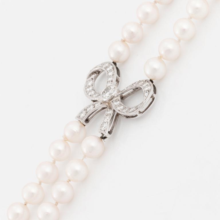 A cultured pearl necklace with a 14K white gold bow pendant set with round brillliant-cut diamonds.