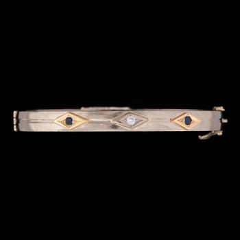 ARMRING, 18 k vitguld med briljantslipad diamant ca 0.05 ct samt 2 fasettslipade safirer. Vikt ca 33 g.