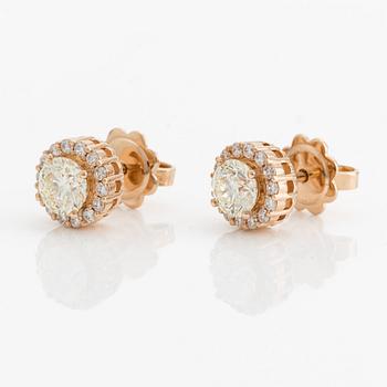 A pair of 18K gold earrings with round brilliant-cut diamonds.