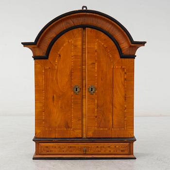 A first half of the 18th century late baroque elm veneered wall cabinet.