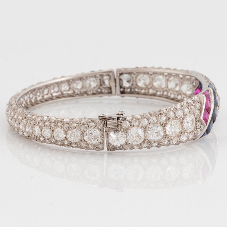 A platinum bangle set with old- and rose-cut diamonds and faceted sapphires and rubies.