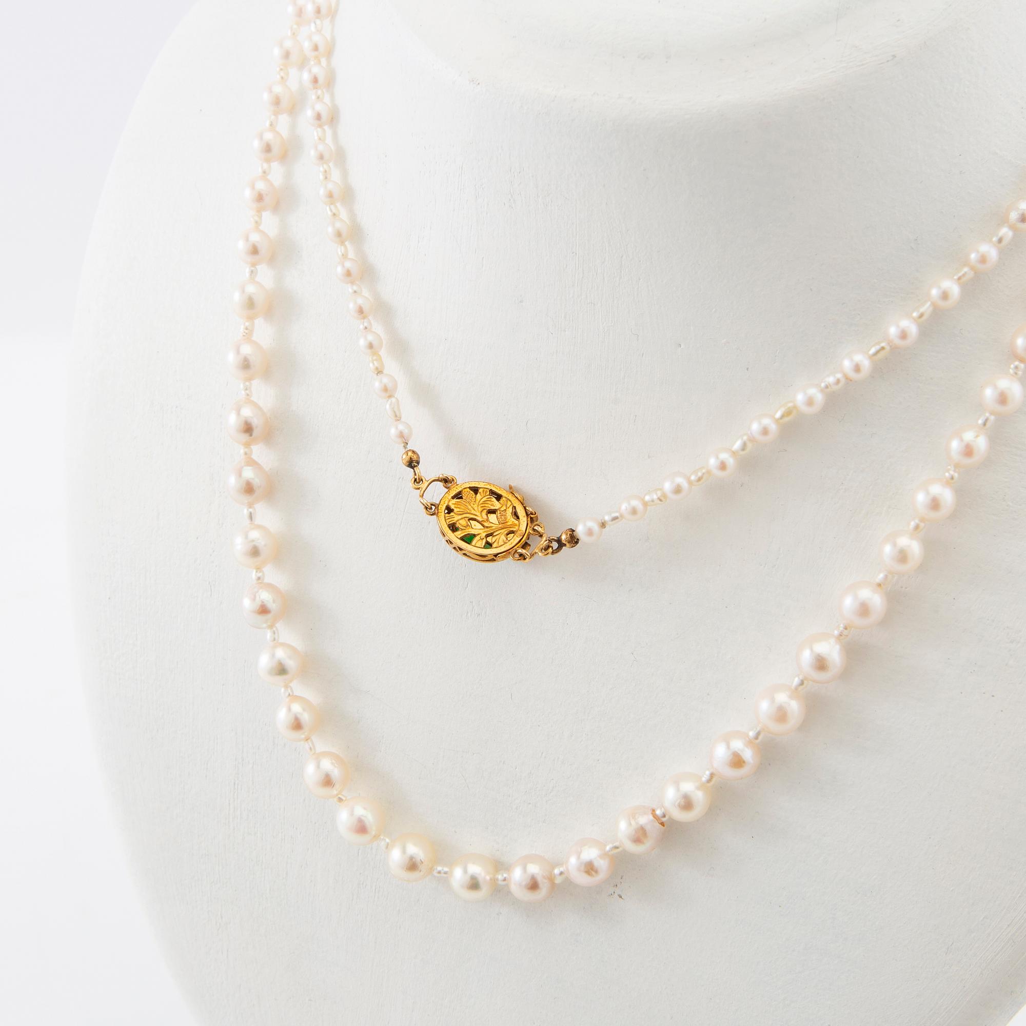 Necklace of cultured pearls with a clasp of 18K gold and cabochon-cut green stone.