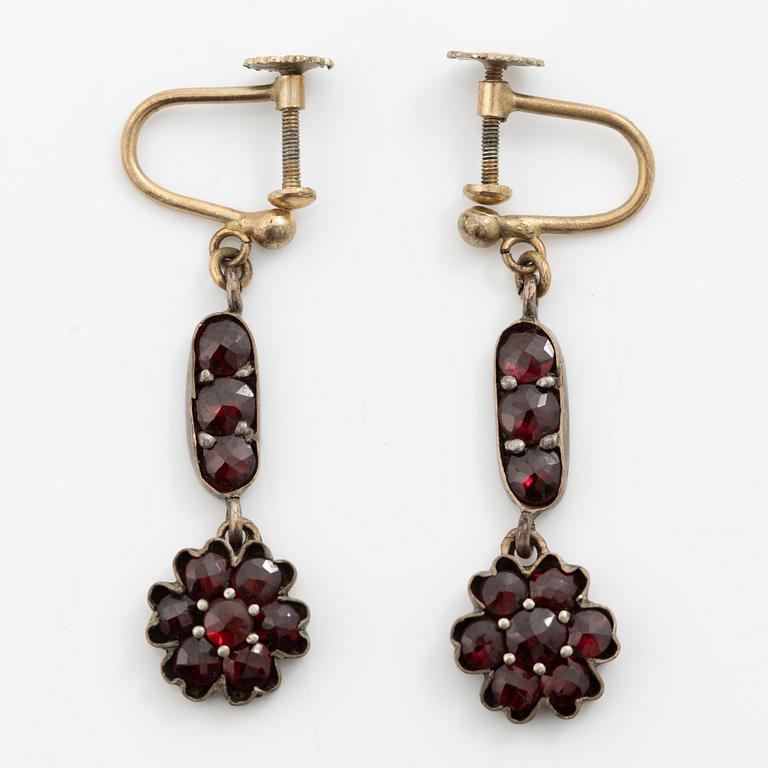 Garniture, necklace/bracelet and earrings in silver with garnets in the form of floral motifs, around the turn of the 20th century.