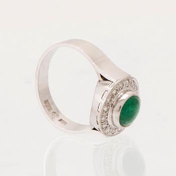 An 18K white gold ring set with a cabochon-cut emerald and round single-cut diamonds.