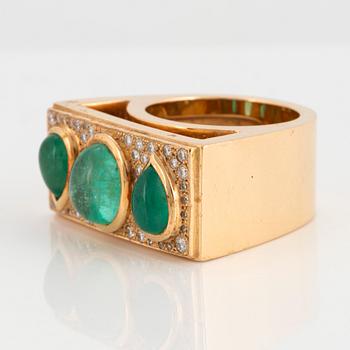 An 18K gold ring set with cabochon-cut emeralds and round brilliant-cut diamonds.