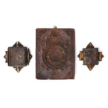 A copper reousse placque and two Tibetan pendants, 19th /20th Century.