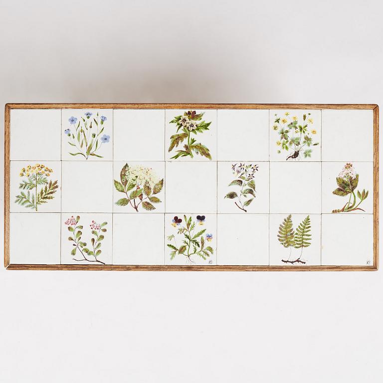 a Swedish Modern coffee table, decorated with Jobs' ceramic tiles, signed and dated 1941.