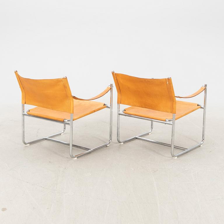 A pair of metal and leather arm chairs by DUX.