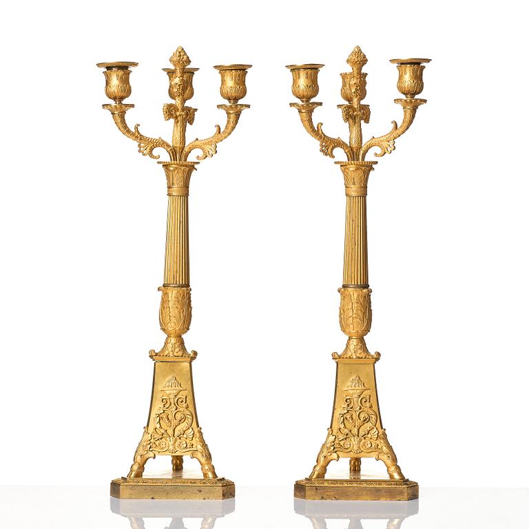 A pair of French Empire three-branch ormolu candelabra, early 19th century.