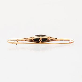 A 14K white and red gold brooch set with round brilliant-cut and rose-cut diamonds and a black stone.