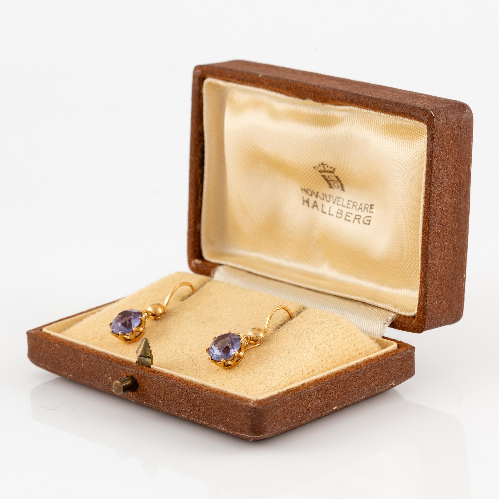 A pair of earrings in 18K gold with purple stones.