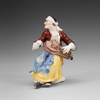 1406. A porcelain figure of a begger playing an instrument, 1740's, presumably Meissen.