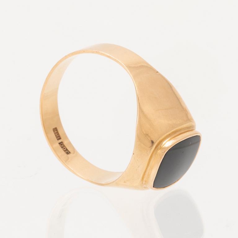 An 18K gold ring set with a black stone.