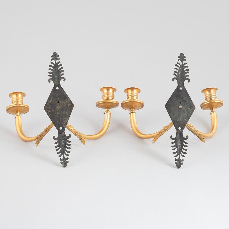 A pair of Empire-style two-branch patinated and gilt bronze appliques, 20th century incorporating older elements.