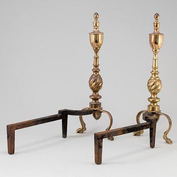 A pair of  ornate brass urn top cast iron fireplace fire dog andirons from around the year 1900.