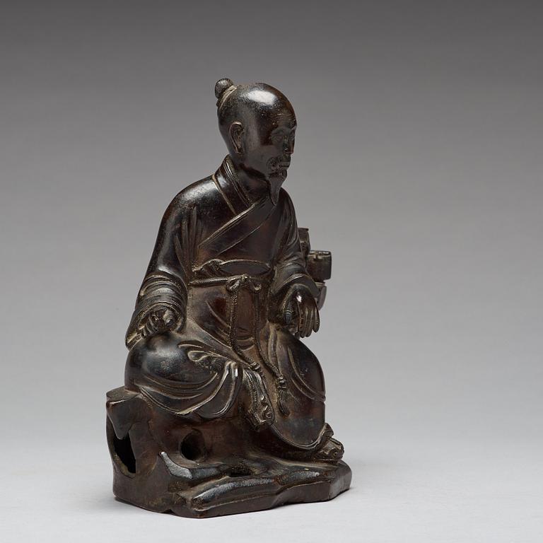 A bronze sculpture of a seated scholar with books, Qing dynasty (1644-1912).