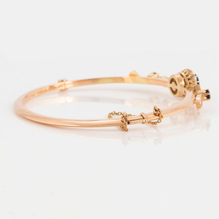 An 18K gold bangle set with faceted sapphires and old-cut diamonds.