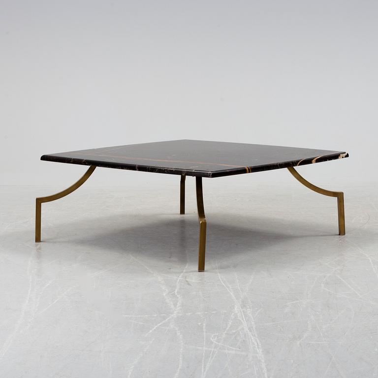 A modern Italian coffee table with black marble top on metal legs.