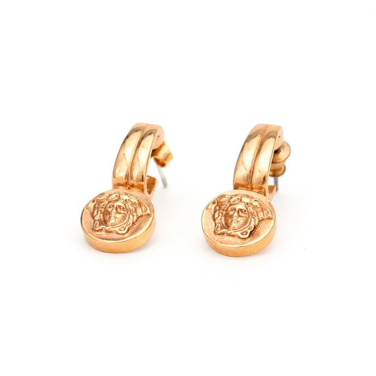 VERSACE, a pair of gold colored earrings.