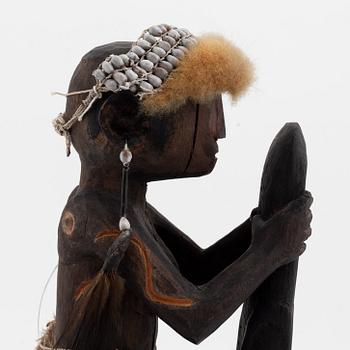 An Asmat carving of a woman holding an ax, Yamas, Jeni, 20th Century.