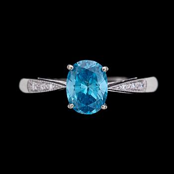 RING, behandlad ovalt briljantslipad blå diamant, ca 1 ct,  med små vita briljantslipade diamanter på sidorna.