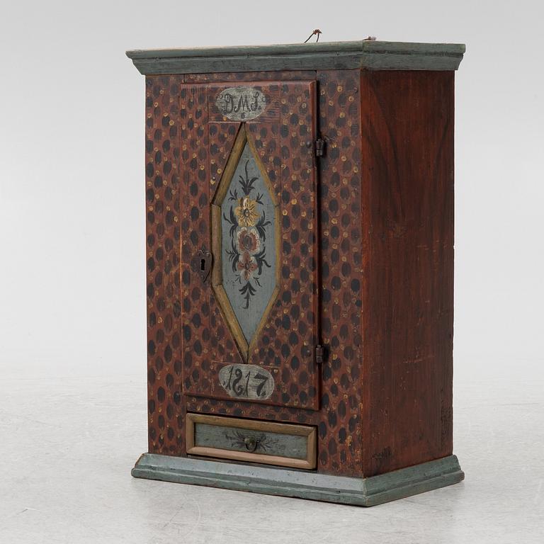 A painted wall cabinet, dated 1817.
