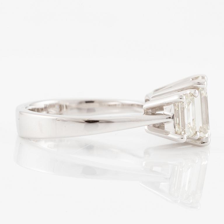 An 18K white gold ring set with three emerald-cut diamonds.