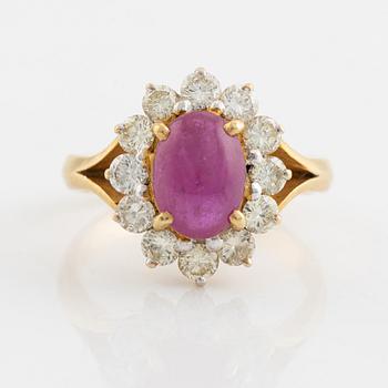An 18K gold ring set with a cabochon-cut ruby and round brilliant-cut diamonds.